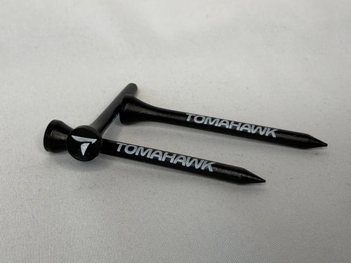 Two black wooden Tomahawk golf tees with white branding, displayed on a light gray background.